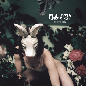 cover art for You Never Know. A woman crouching in a garden wearing a bunny mask