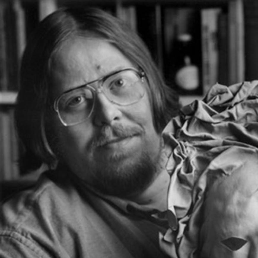 black and white photo of a man with beard, glasses and long hair