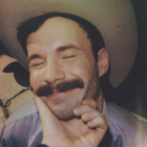 cover, American Rough: A closeup of a smiling cowboy's face, eyes closed, his chin cupped affectionately by a man's hand.